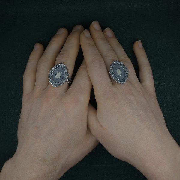 Bague scarabée noir sacré des égyptiens dans son cadre ovale mouluré, esprit baroque et musée en argent massif portée sur mains | Res Mirum