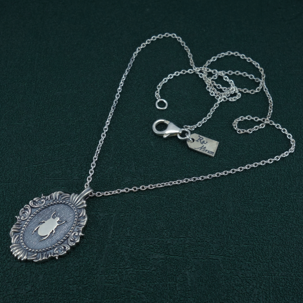 Petit collier scarabée noir égyptien dans cadre ovale baroque inspiré des cabinets de curiosités de fabrication artisanale. Vue complet | Res Mirum