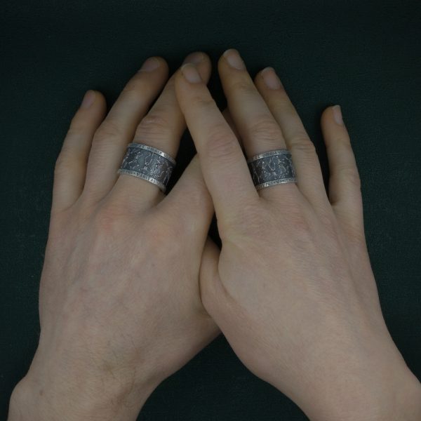 Anneau représentant une danse de squelettes, inspiré des danses macabres médiévales, bijou avec inscriptions en latin de type memento mori. Vue portée sur mains | Res Mirum