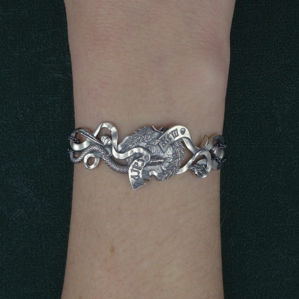 Bracelet comprenant les éléments symboliques d'une vanité de la Renaissance : couronne de lauriers, phylactère gravé Carpe diem, serpent, citron pelé, pinceaux et verre porté sur poignet | Res Mirum