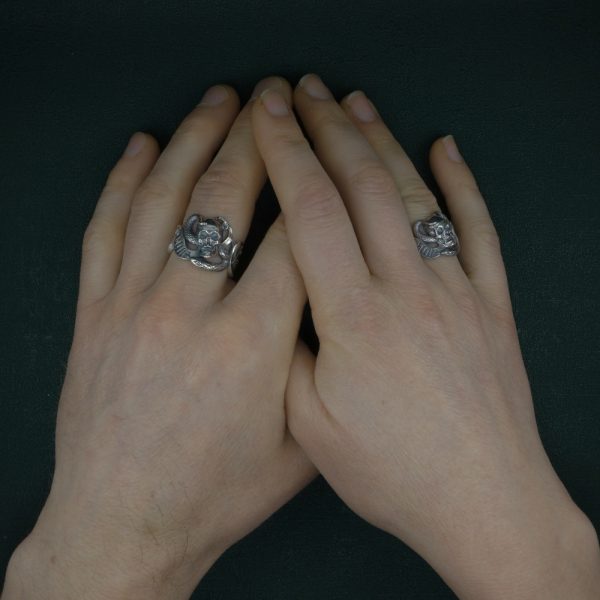 Bague memento mori représentant un crâne au centre d'éléments symboliques : cerises, compas, serpent, phylactère... bijou typique des vanités de la Renaissance. Vue portées | Res Mirum
