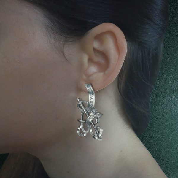 Boucles d'oreilles représentant une nature morte, bijou allégorie de la mort avec les symboles du serpent, la plume d'écriture, la bougie, coquelicot et épi de blé, phylactère. Vue portée grand modèle | Res Mirum
