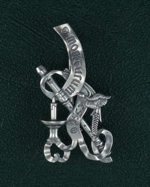 Broche représentant une nature morte, bijou allégorie de la mort avec les symboles du serpent, la plume d'écriture, la bougie, coquelicot et épi de blé, phylactère. Vue de face | Res Mirum